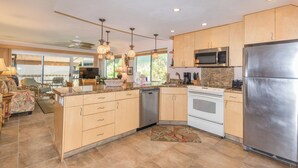 Une cuisine moderne avec des meubles en bois, des appareils électroménagers en acier inoxydable et des luminaires suspendus.