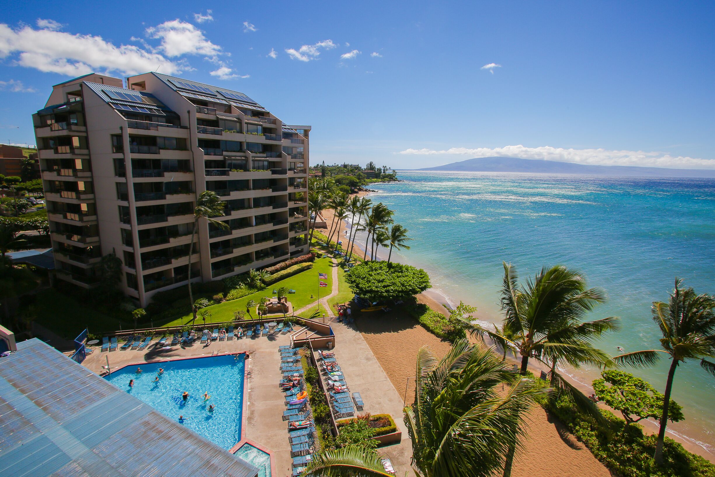A hotel with a pool, beach, and ocean view.