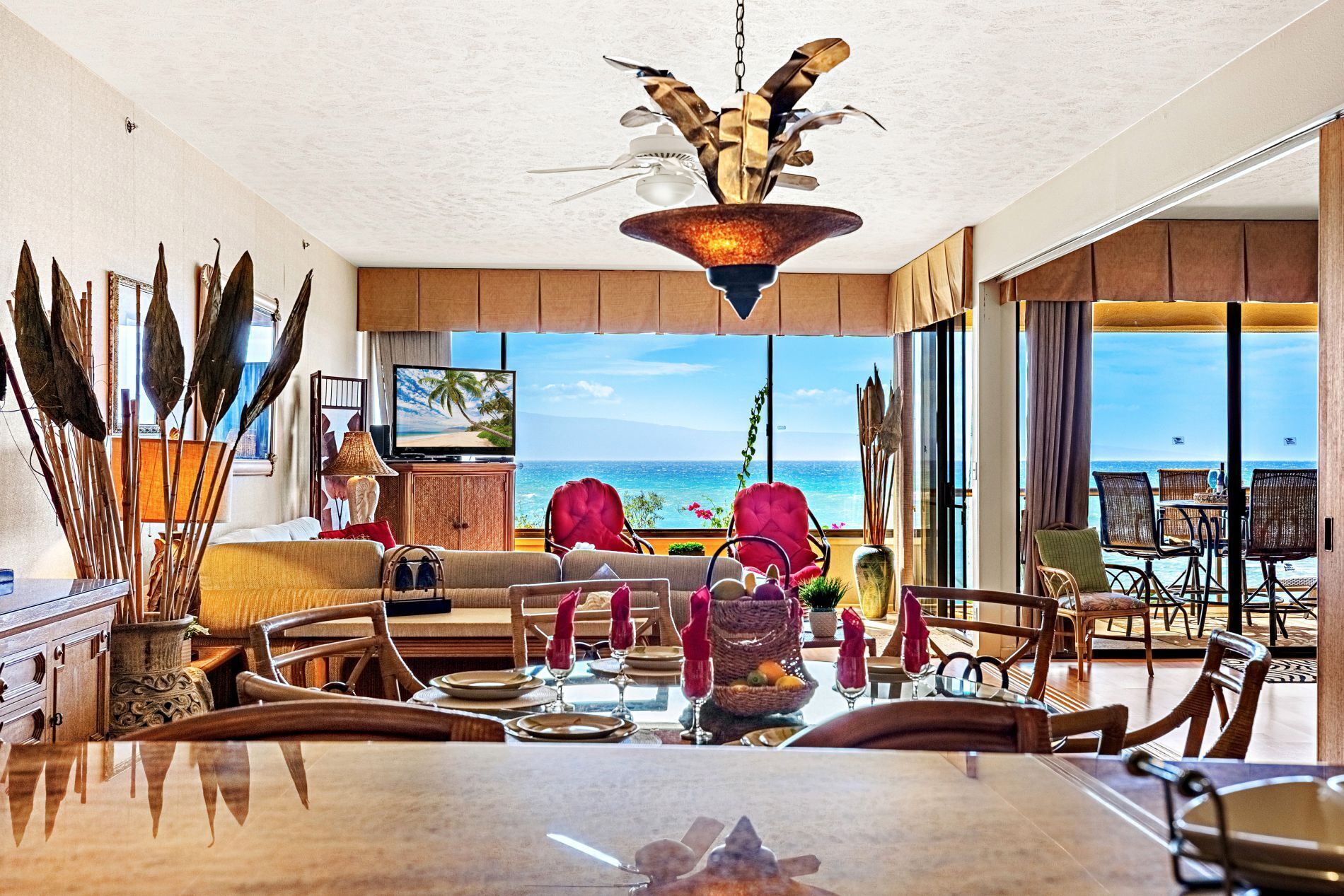 A spacious living area with a large dining table, comfortable seating, and a view of the ocean.