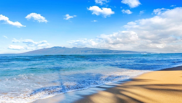 A beach with clear blue water, a sandy shore, and distant mountains under a partly cloudy sky. - Extended Summer Special $250n 9/1-11/20- 2bd Oceanfront View-SK 344 Sullivan (Lahaina)