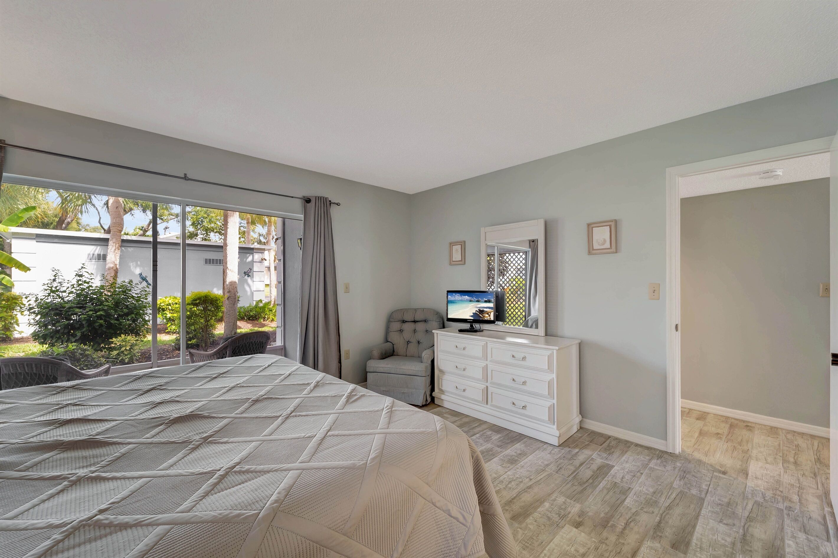A bedroom with a bed, a dresser, a television, and a window with curtains.