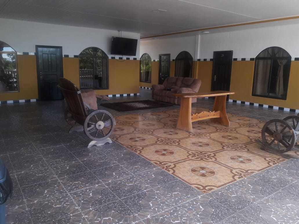A spacious lobby with a patterned floor, a sofa, a wooden table, and a television mounted on the wall.