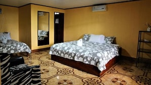 Una habitación de hotel con dos camas, un espejo, una mesita y una silla.
