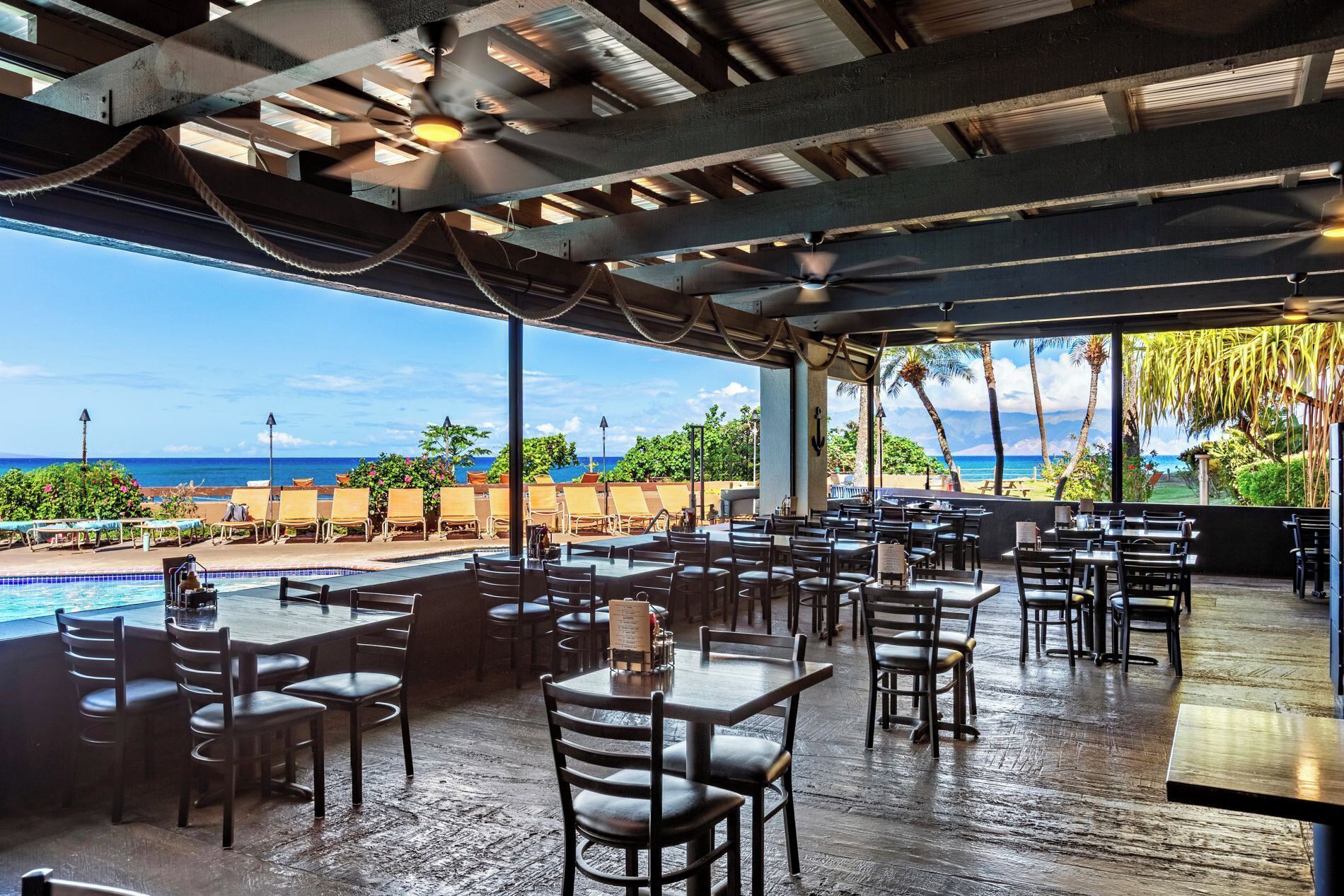 An outdoor dining area with a pool and a view of the ocean.