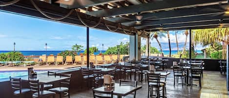 An outdoor dining area with a pool and a view of the ocean.