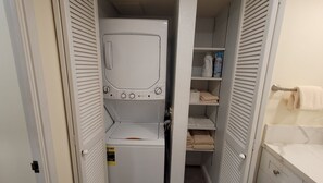Une buanderie équipée d’un lave-linge et d’un sèche-linge, d’une étagère pour les articles de toilette et d’un porte-serviettes.