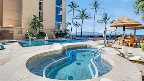 Zona de piscina de hotel con un jacuzzi, sillas de descanso y vistas al océano.