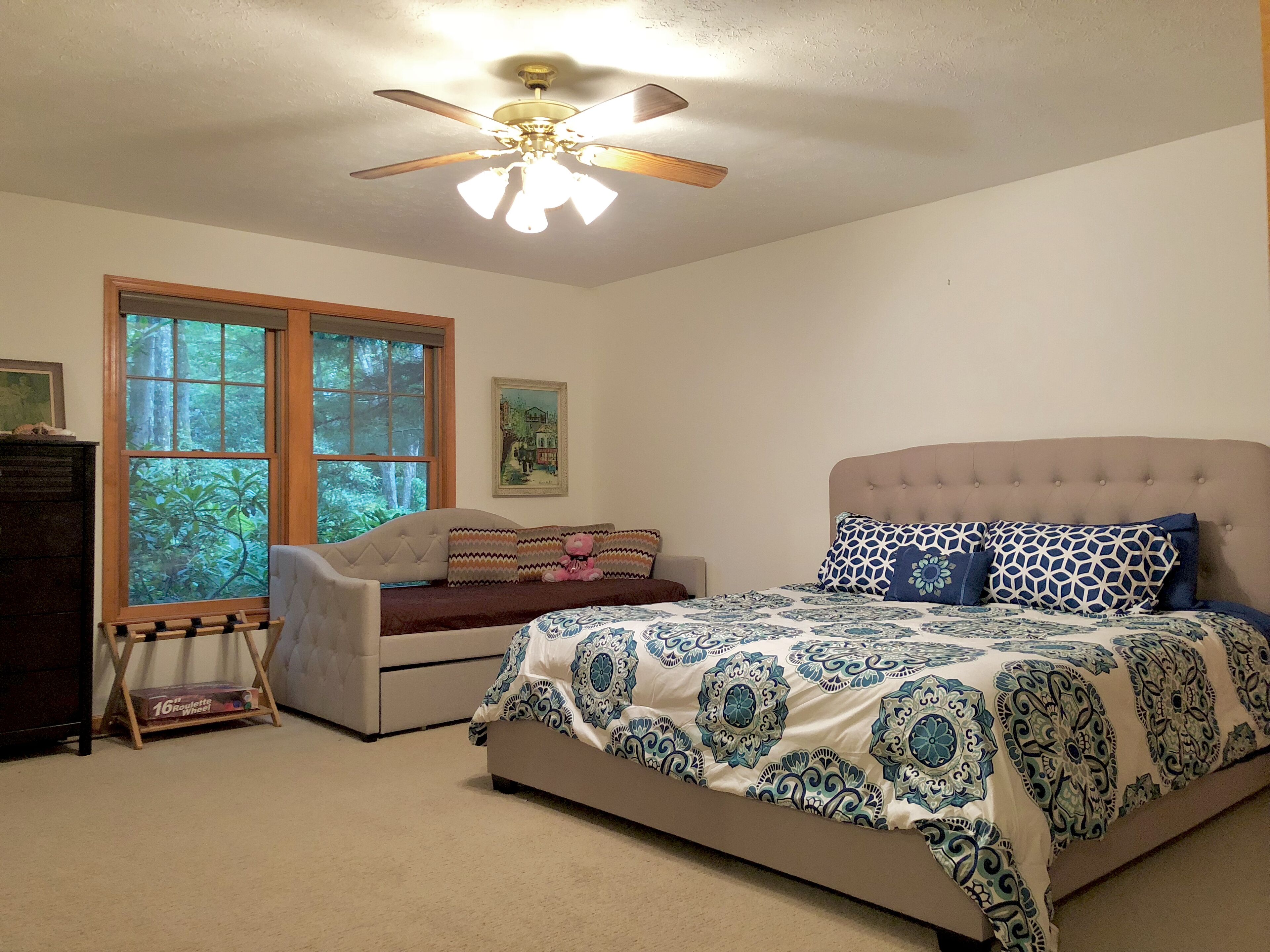 A bedroom with a bed, a chair, a desk, and a ceiling fan.