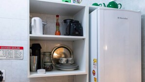 A kitchen with a white refrigerator, a coffee maker, a kettle, and a jar. There is a sign with house rules on the wall. - LIVING ROOM HALF A BLOCK AWAY – CHANNEL 6 – AIR CONDITIONING, WI-FI, CABLE TV, WASHER/DRYER AND GARAGE (Santos)