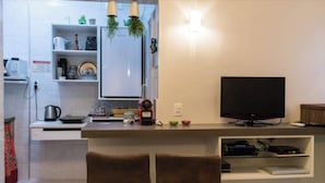 A modern kitchen with a built-in TV, two bar stools, and a small bar area. - LIVING ROOM HALF A BLOCK AWAY – CHANNEL 6 – AIR CONDITIONING, WI-FI, CABLE TV, WASHER/DRYER AND GARAGE (Santos)