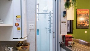 A modern kitchen with a built-in oven, a glass door shower, and a dining area with a red appliance. - LIVING ROOM HALF A BLOCK AWAY – CHANNEL 6 – AIR CONDITIONING, WI-FI, CABLE TV, WASHER/DRYER AND GARAGE (Santos)