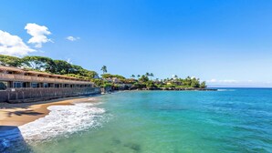 Un hôtel situé en bord de mer, doté d’un mur en pierre, offrant une vue sur l’océan et entouré d’une végétation tropicale.