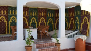 A covered outdoor seating area with patterned wall decor, a staircase, and potted plants. - Traditional riad with modern comfort 6/8 per in the heart of the medina. (Meknès)