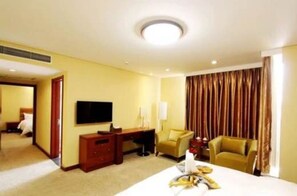 A hotel room with a bed, a desk, a television, and a sofa.