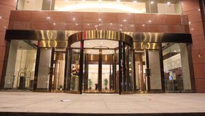 L’entrée d’un hôtel avec une porte tournante, des portes en verre et un sol carrelé.