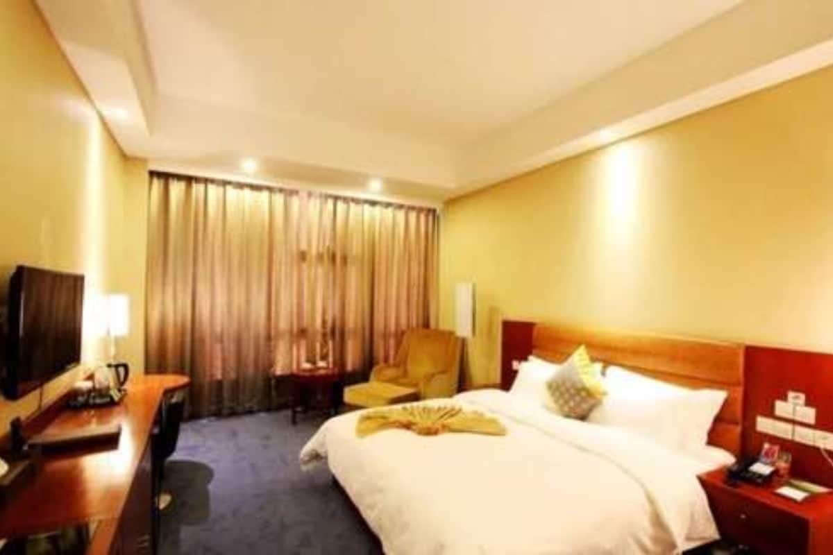 Ein Hotelzimmer mit Bett, Schreibtisch, Stuhl, Fernseher und einem fensterbepflanzten Fenster.
