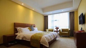 Une chambre d’hôtel avec un grand lit, un bureau, deux chaises et un téléviseur fixé au mur.