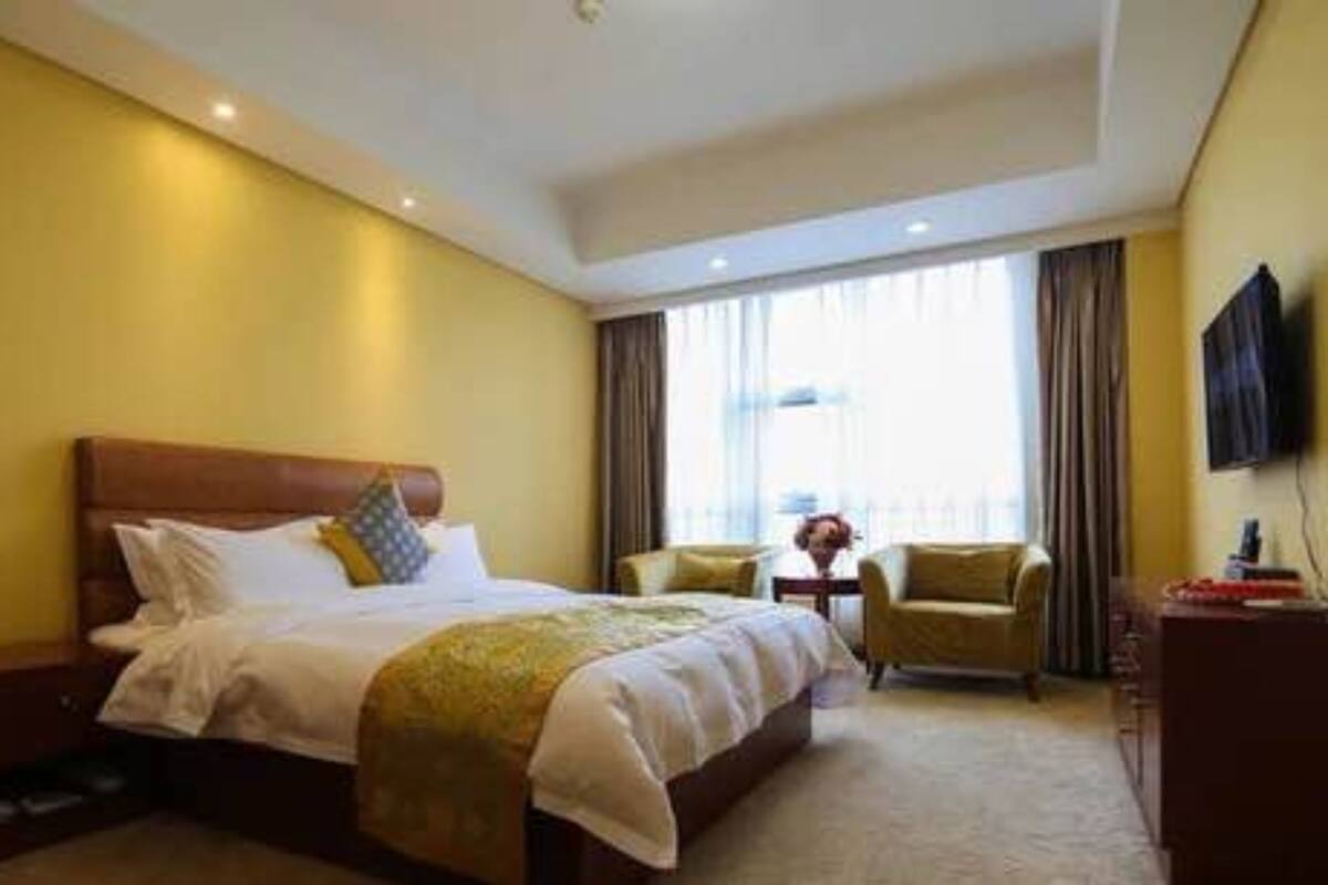 Ein Hotelzimmer mit einem großen Bett, einem Schreibtisch, zwei Stühlen und einem an der Wand befestigten Fernseher.