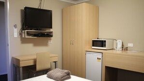 A hotel room with a bed, a desk, a television, a microwave, and a small refrigerator. - Irish Club Accommodation (Parkside)