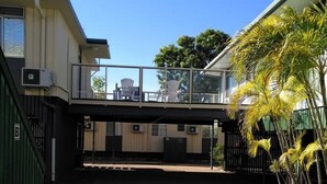 A building with a covered walkway, air conditioning units, and a paved entrance area. - Irish Club Accommodation (Parkside)