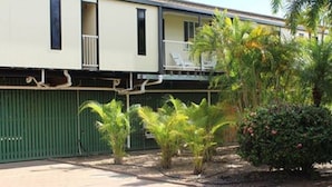 A two-story building with a balcony on the second floor. There are several palm trees and shrubs in the front yard. - Irish Club Accommodation (Parkside)