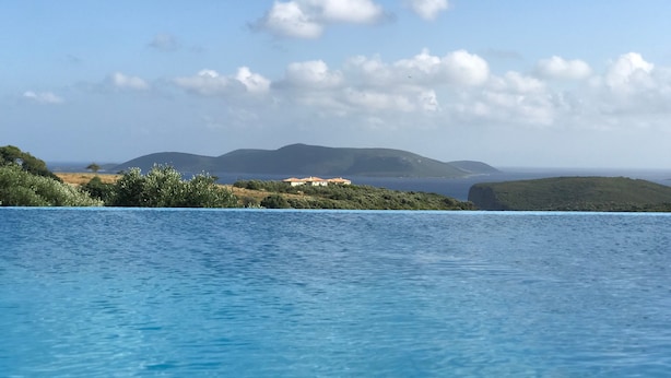 Une piscine offrant une vue sur des collines lointaines et un bâtiment.