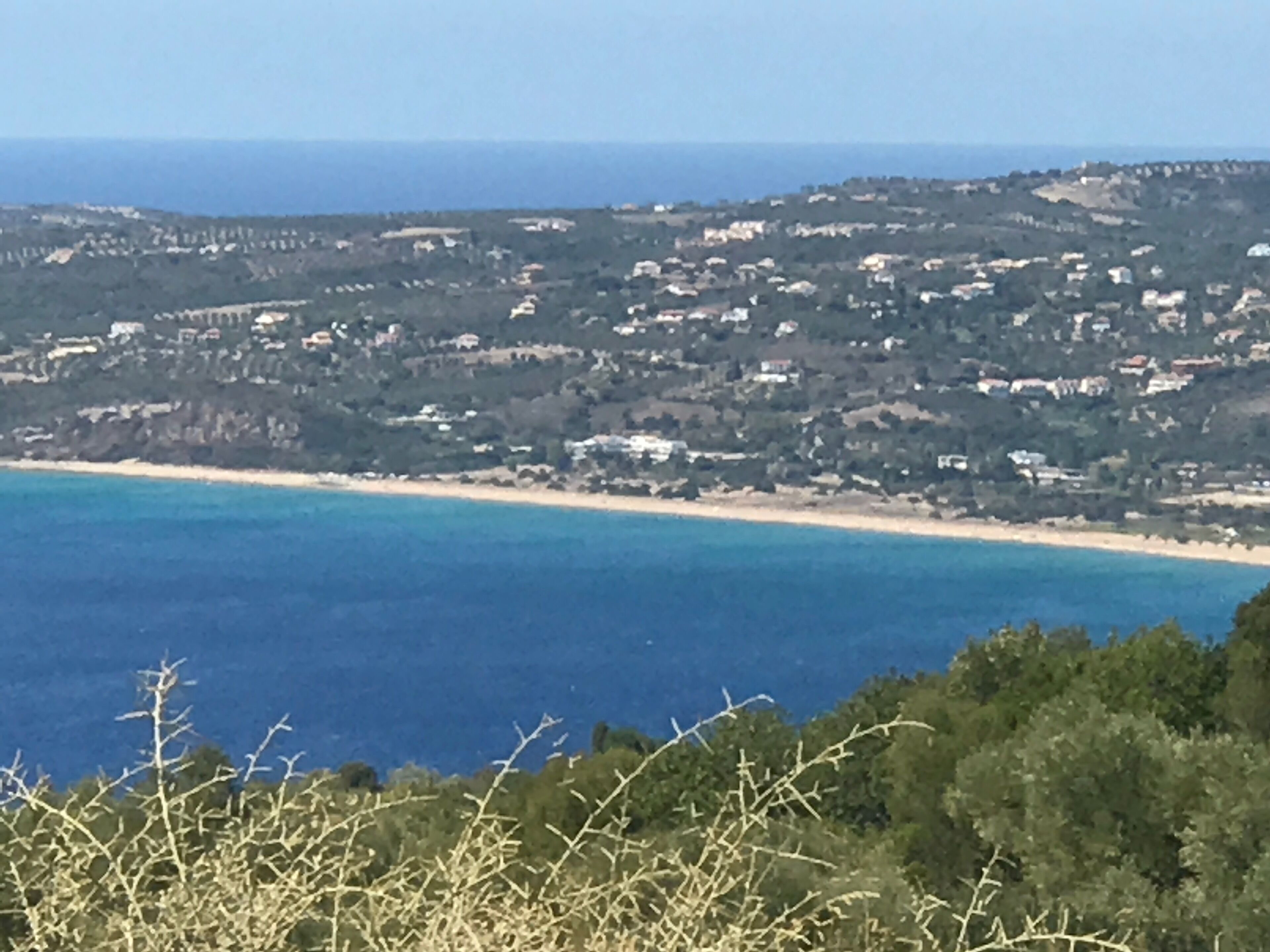Eine Küstenlandschaft mit Strand, Gebäuden und Grünflächen.