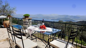 Eine Terrasse mit Tisch für zwei Personen, Blick auf die Berge und einem klaren Himmel.