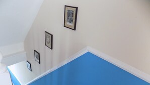 Une pièce avec un banc rembourré bleu, des murs blancs et trois tableaux encadrés accrochés au mur.