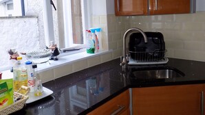 Une cuisine dotée d’un plan de travail noir, d’un évier en acier inoxydable et d’armoires en bois.