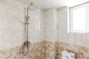 Ein Badezimmer mit Dusche, Marmorwänden und einem Fenster.
