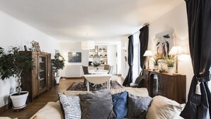 En moderne stue med sofa, spisebord og et køkken i baggrunden.