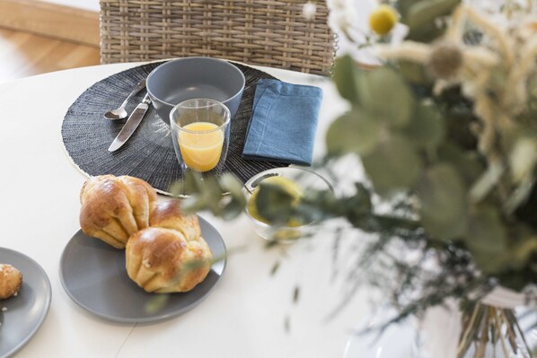 A breakfast setting with a plate of croissants, a glass of orange juice, and a bowl on a table. - Sweet Home Saint Malo Paramé. Beach 50 m away. 2 bedrooms (Saint-Malo)