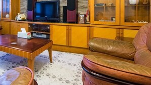 A living room with leather sofas, a wooden coffee table, a television, and a cabinet with glass doors. - Dog House (Taitung)