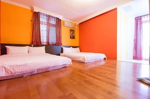 A hotel room with two beds, wooden flooring, orange walls, and a large window with curtains. - Dog House (Taitung)