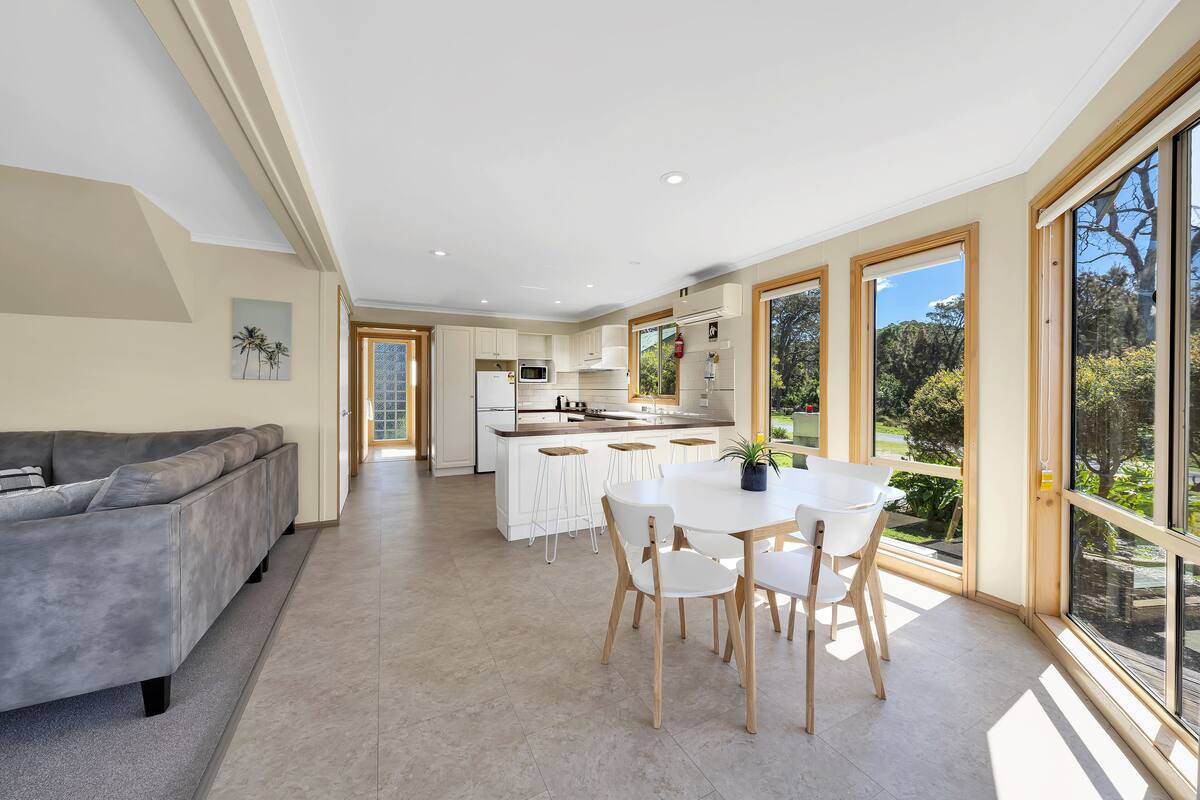 Una cocina moderna con una isla central, armarios blancos y ventanas amplias que dan a vistas del exterior.