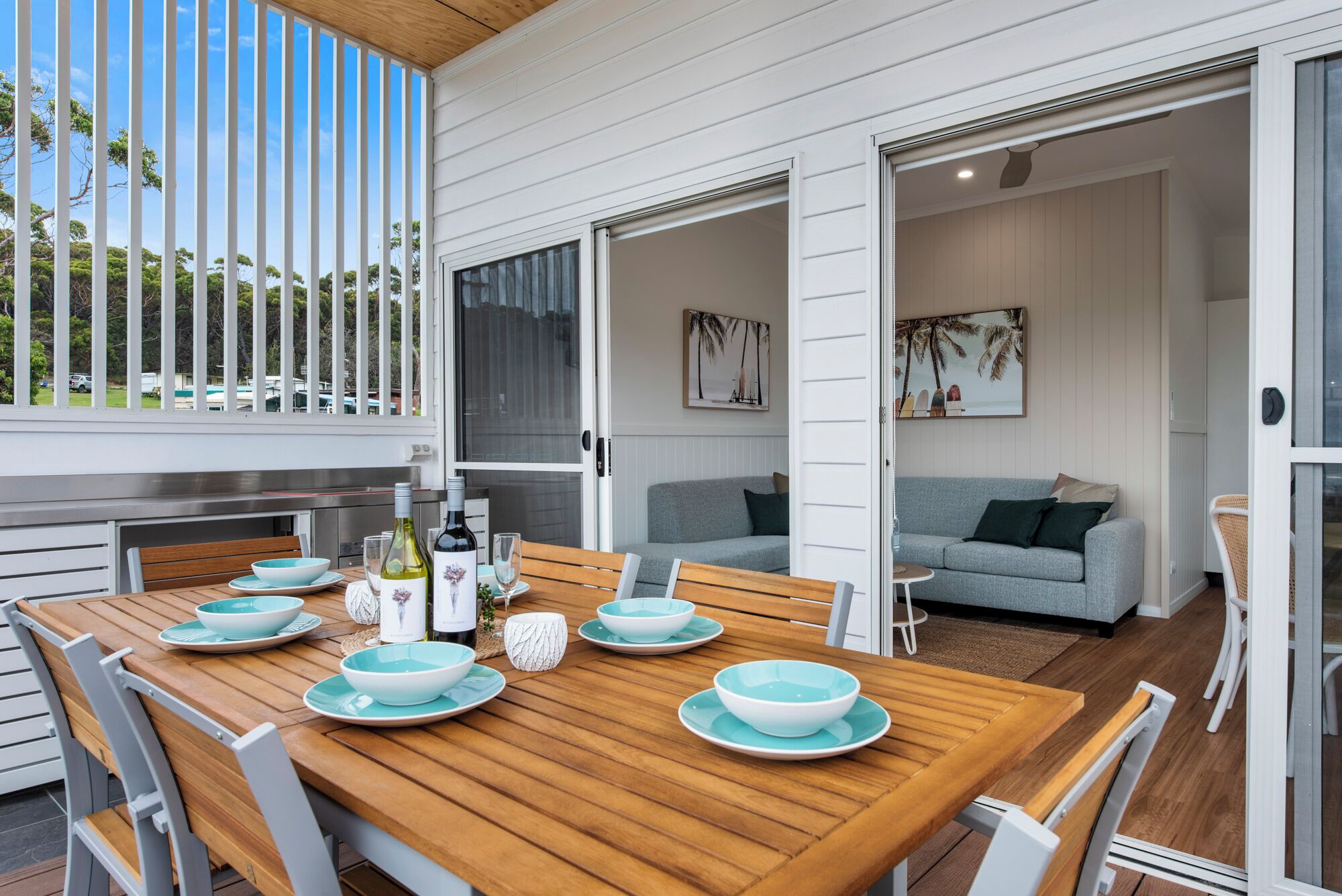 Un comedor con una mesa de madera dispuesta para cuatro personas, rodeado de sillas blancas.