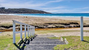 Una escalera que lleva a una playa, con vista al océano y una colina al fondo.