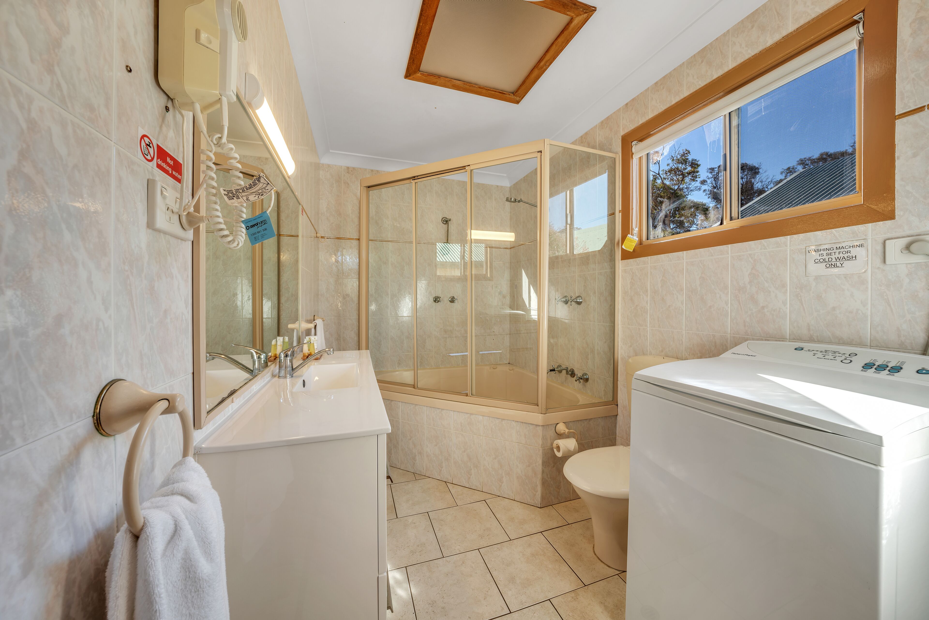 A bathroom with a glass-enclosed shower, a toilet, and a washing machine.