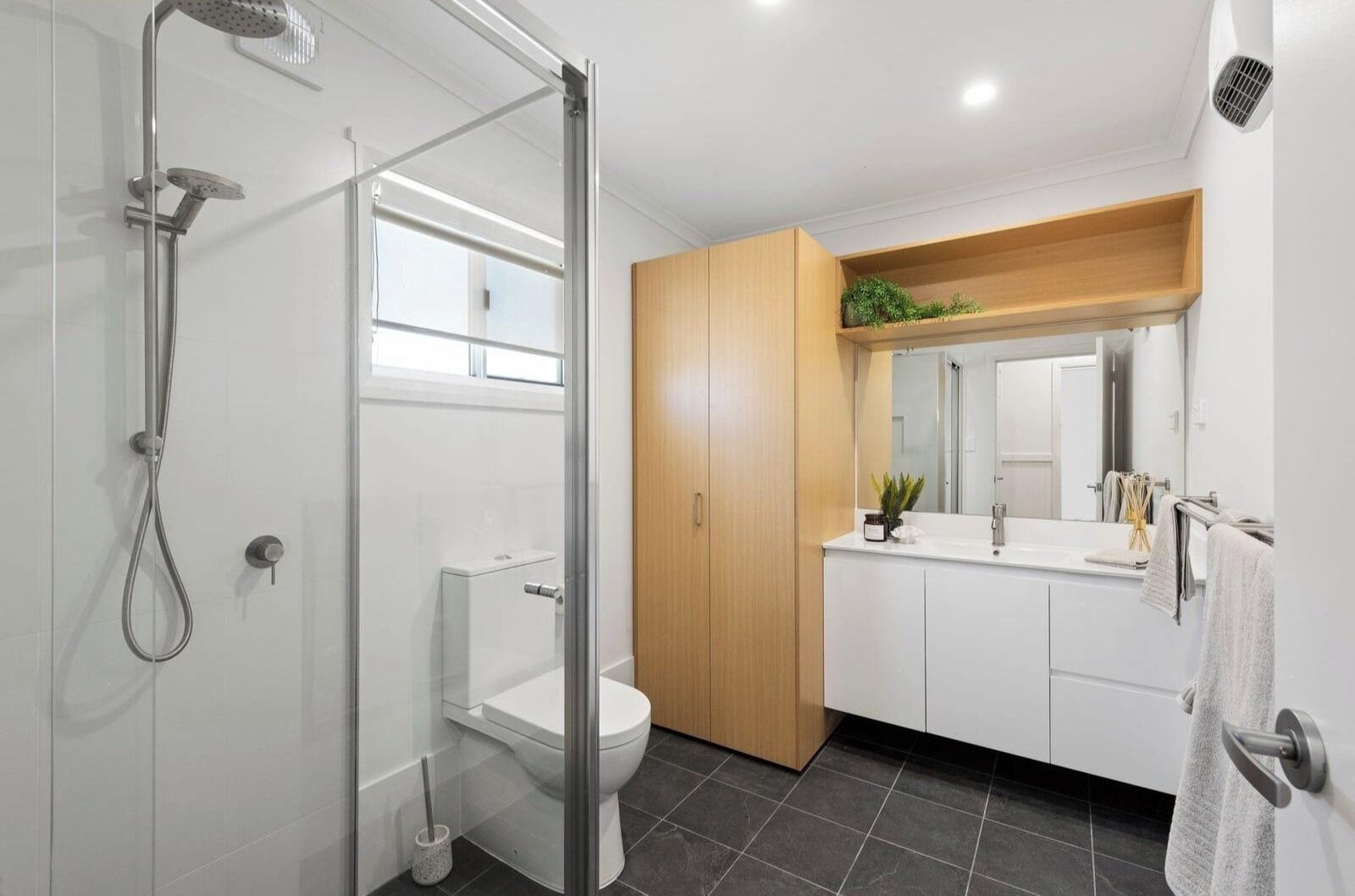 A modern bathroom with a glass-enclosed shower, a toilet, and a vanity with a mirror.