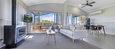 Amplia sala de estar con chimenea, un sofá, una mesa de comedor con sillas y un balcón con vistas.