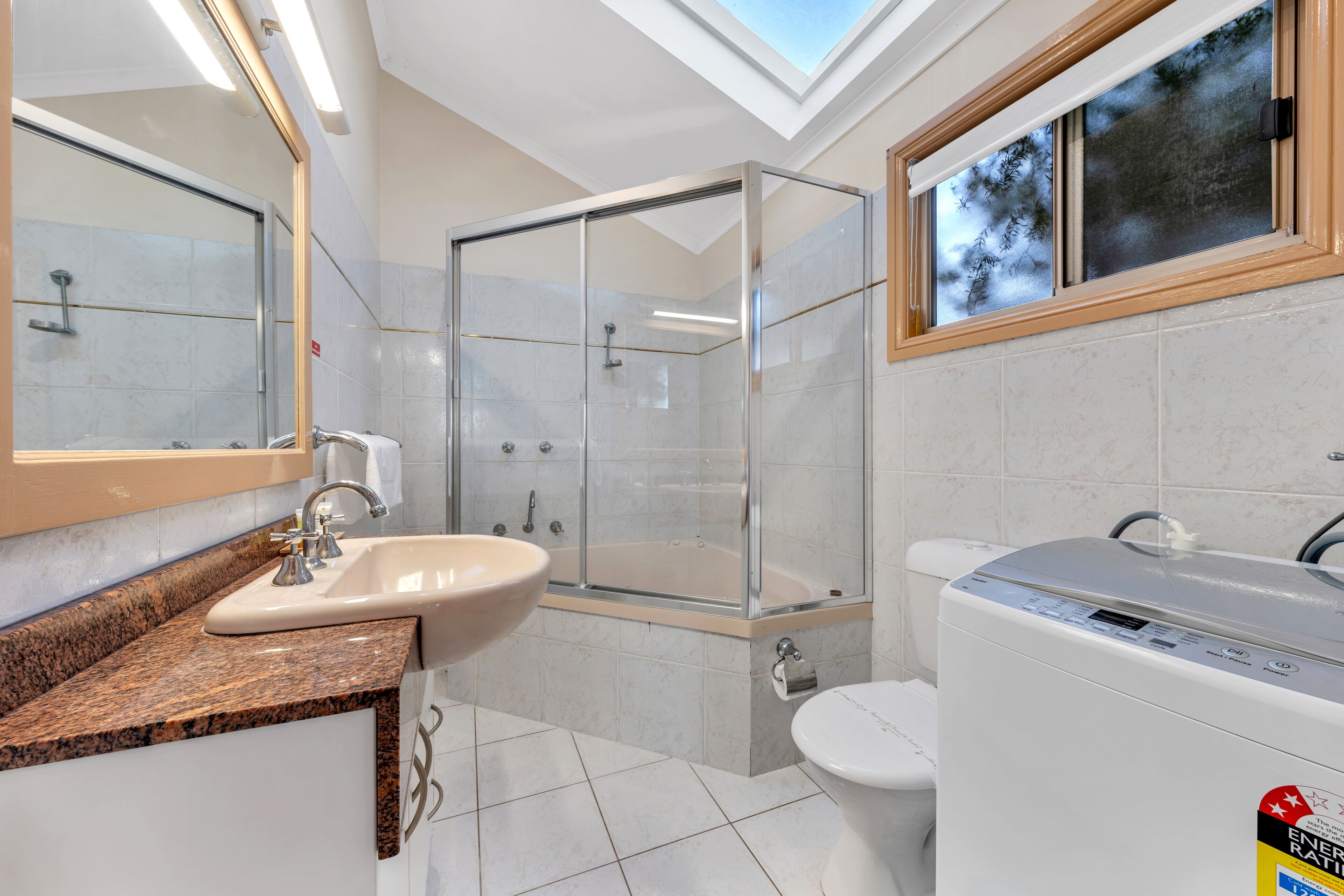 A modern bathroom with a glass-enclosed shower, a sink, a toilet, and a bathtub.