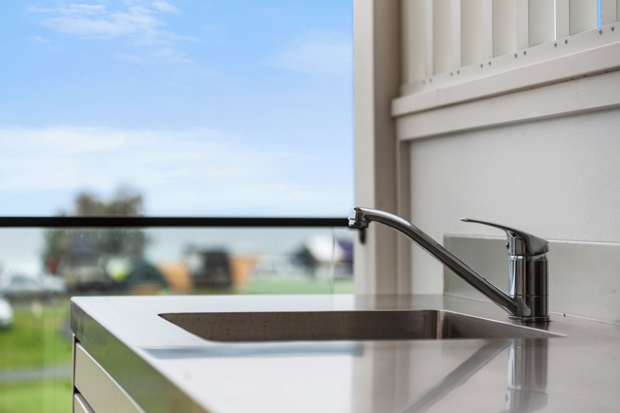 A modern kitchen with a stainless steel sink and a window overlooking a green landscape.