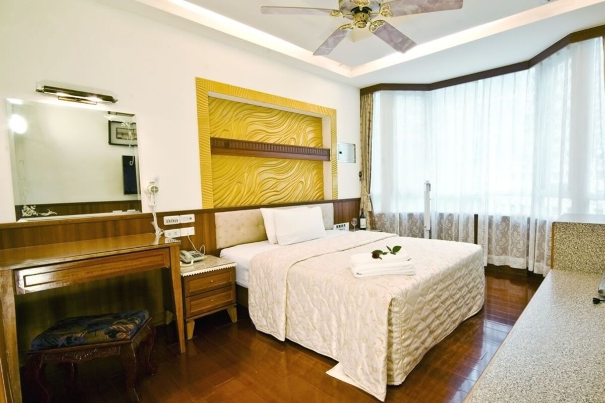 A hotel room with a bed, bedside table, and a television.
