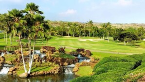 Ein Golfplatz mit Teich, Palmen und einem Wasserfall.
