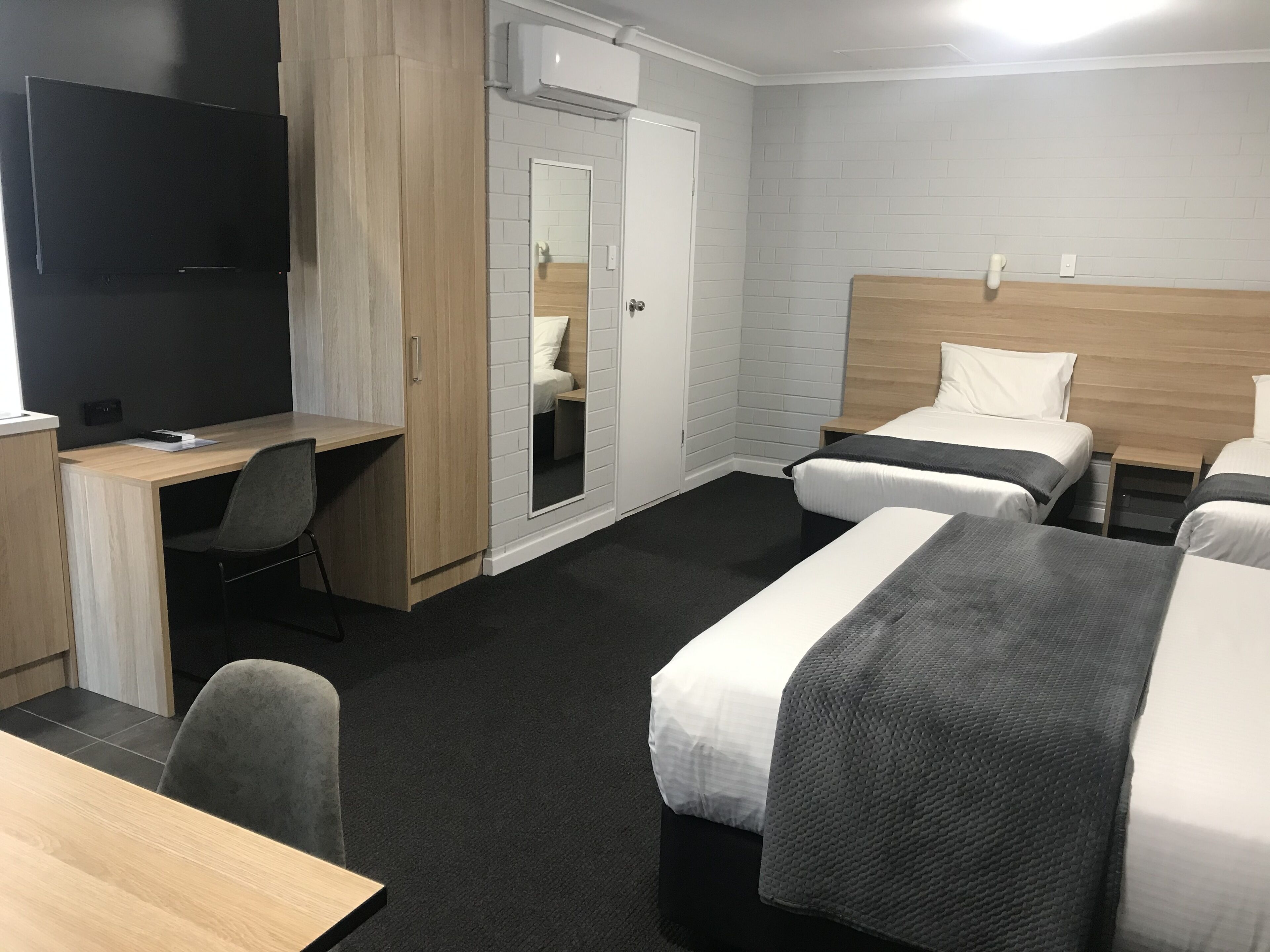 Une chambre d’hôtel équipée d’un bureau, de deux lits, d’une télévision et d’une armoire.