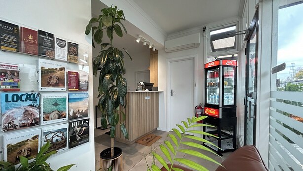 A hotel lobby with a reception desk, a Coca-Cola refrigerator, and various local travel posters on the walls. - Frewville Motor Inn (Frewville)
