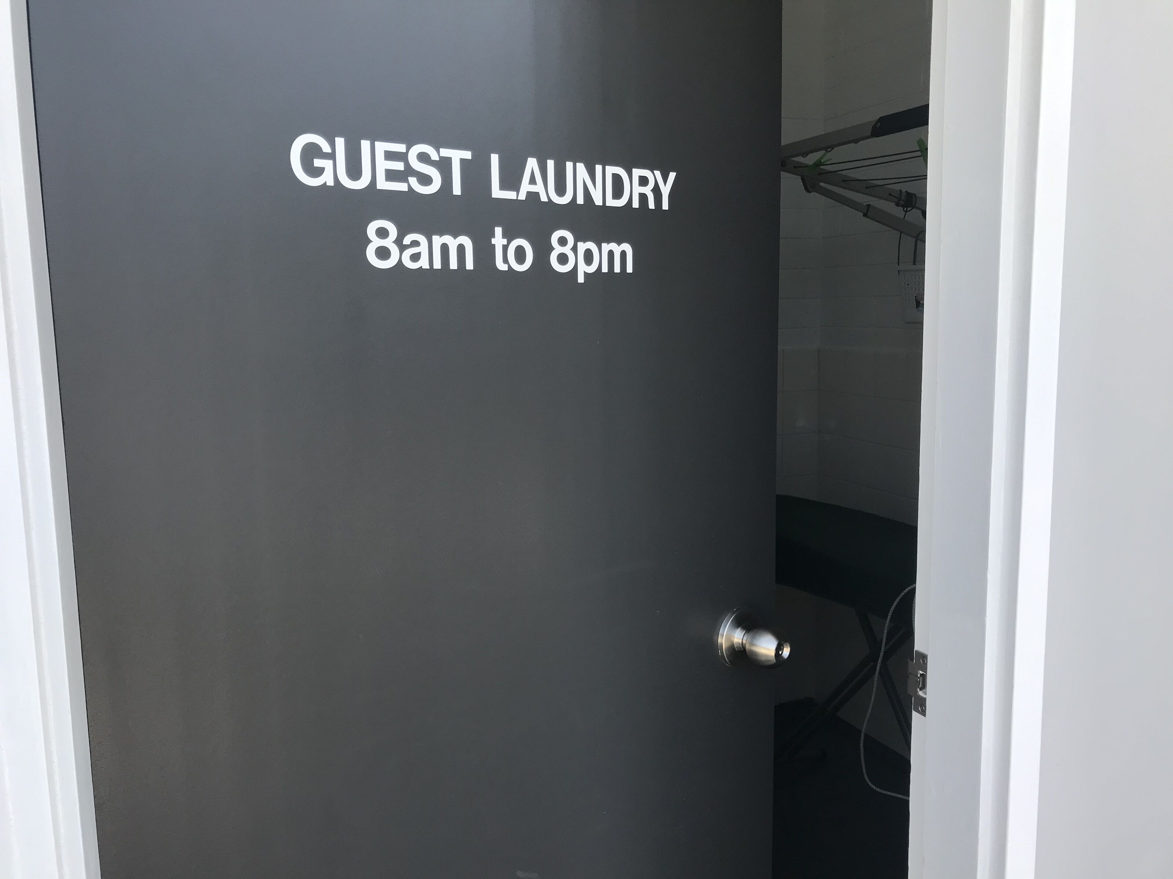 A door with a sign indicating guest laundry hours from 8am to 8pm.