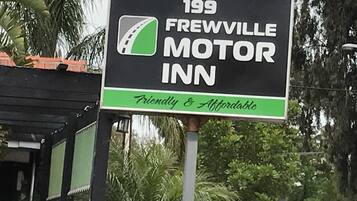 A sign for '199 FREWVILLE MOTOR INN' with a green stripe and a film reel icon.