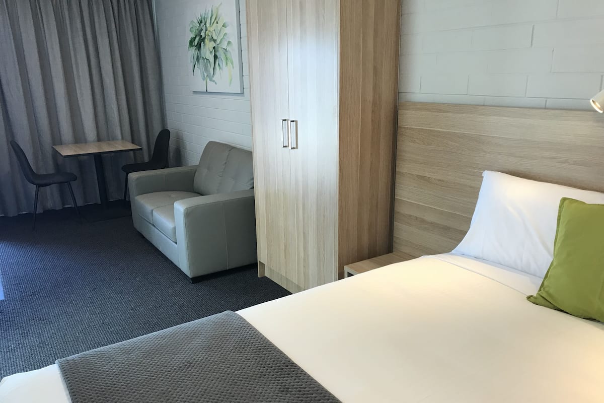 Hotellihuone, jossa on sänky, sohva, pieni pöytä ja tuoli.